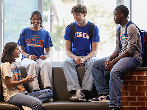 Four students sit on a window ledge, engaged in a lively conversation.